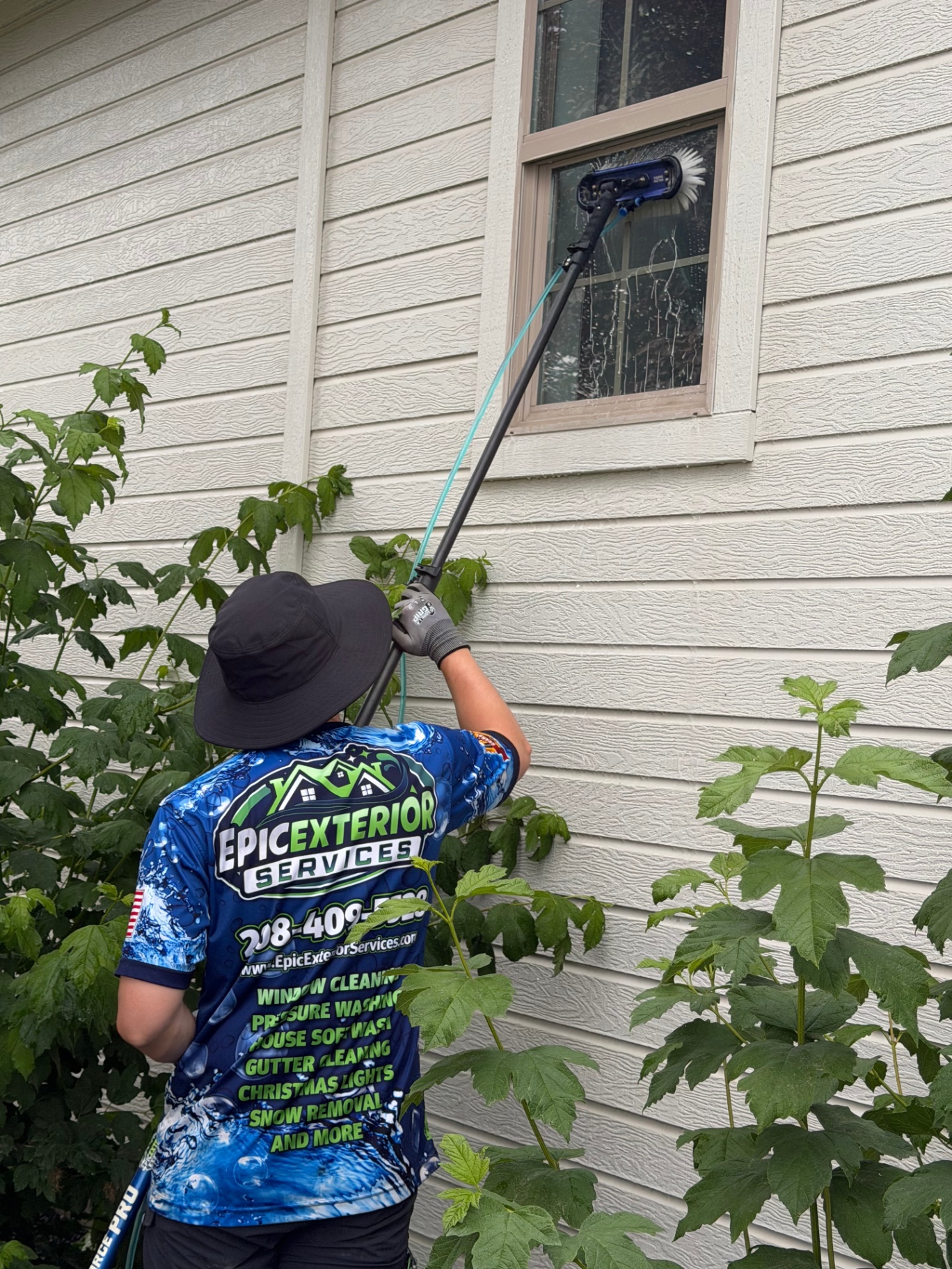 Exterior second-story window cleaning with brush detail on a residential home