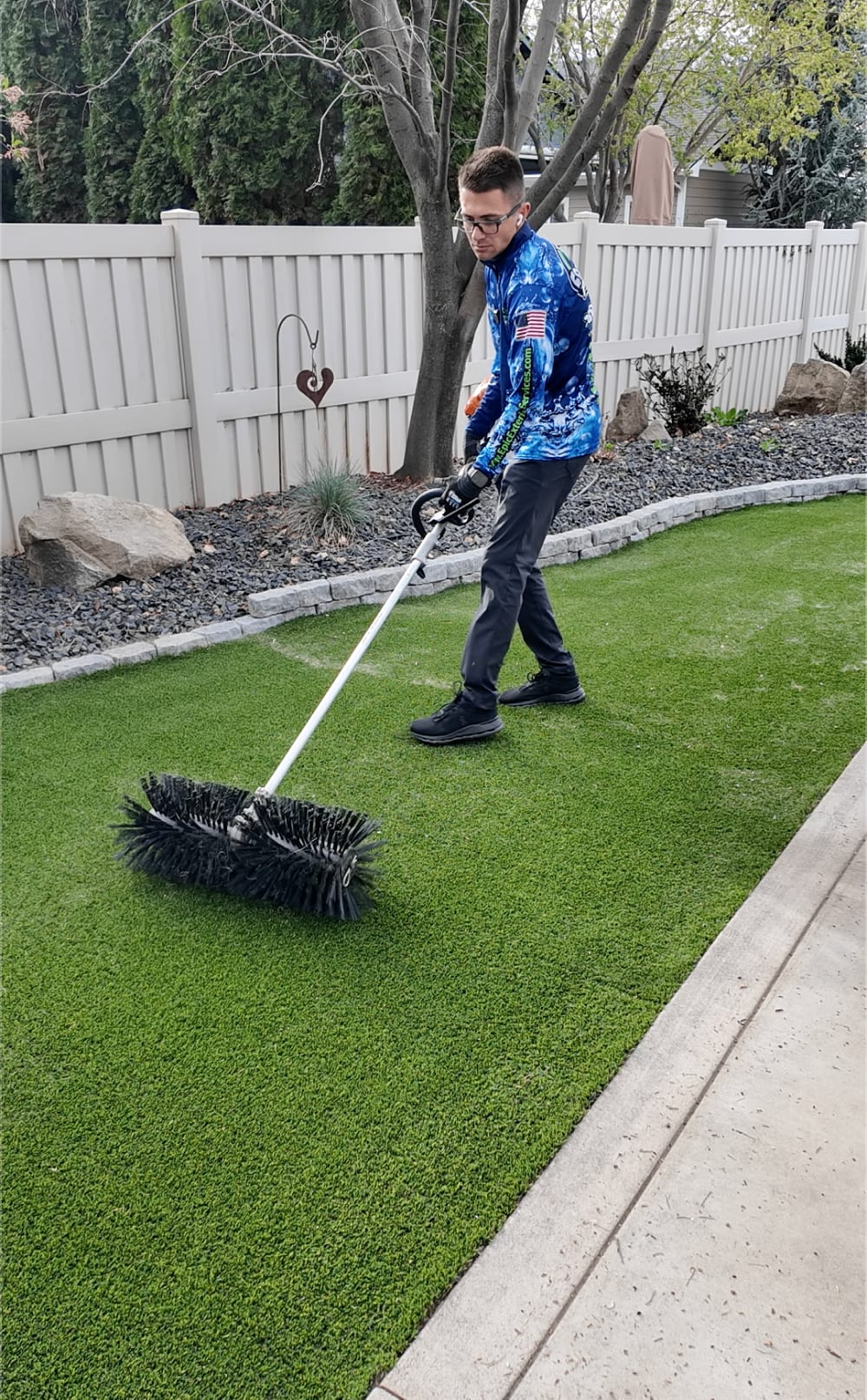 Technician power brushing artificial turf in a Treasure Valley backyard